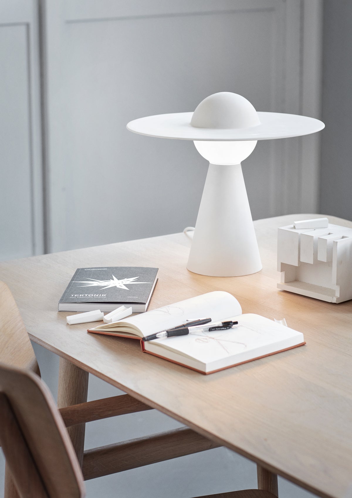 MOEBE Ceramic Table Lamp på et træbord ved en åben notesbog.