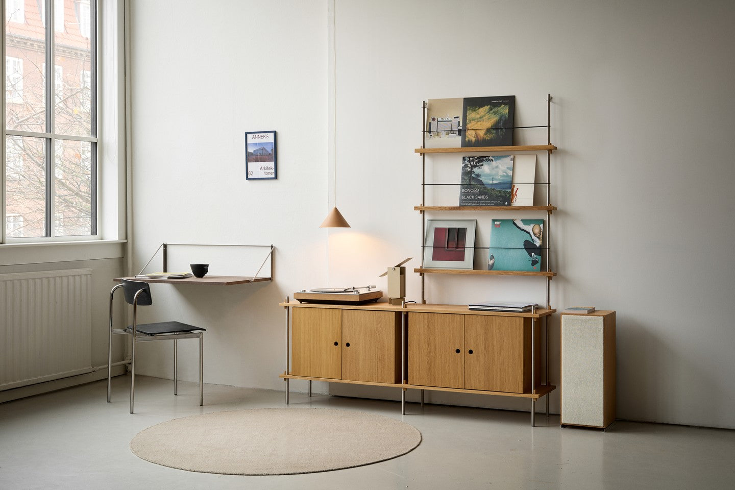 MOEBE Fold-out Desk i en lys stue med reol og skab i træ.